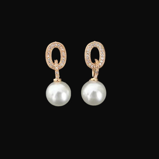 Pearl earrings with gold accents on a gray background