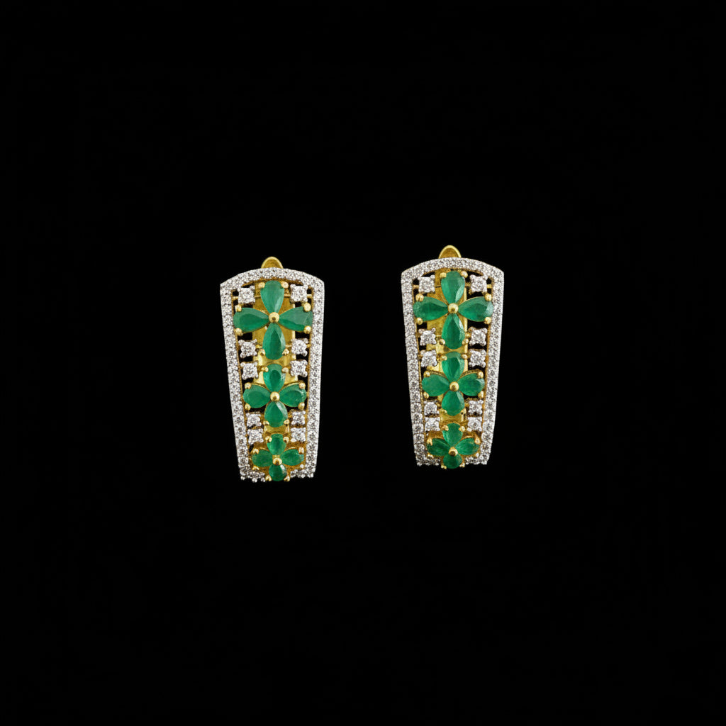 Pair of emerald earrings with a dark background and 'Saheli' branding.