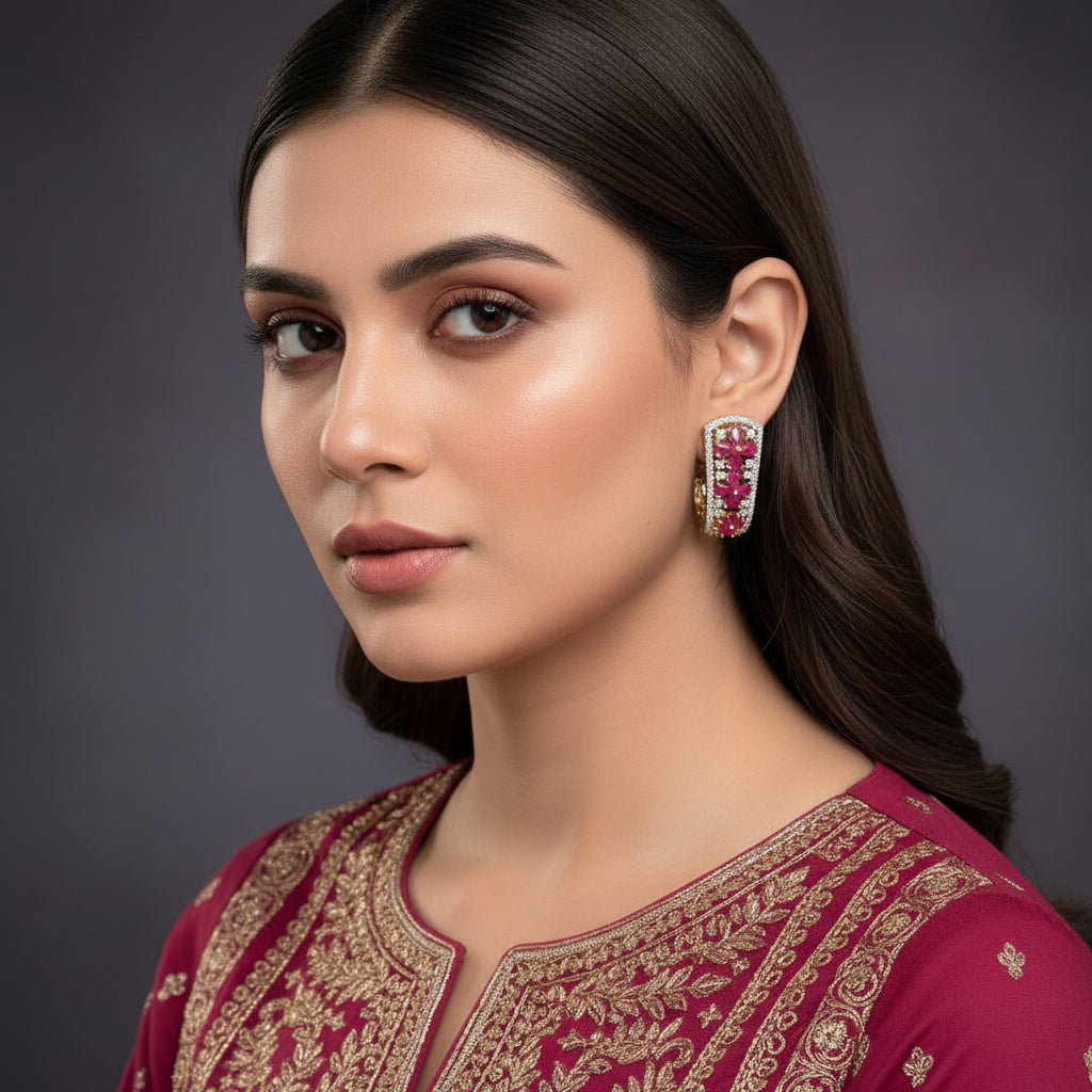 Pair of earrings with pink and gold accents on a gray background, featuring the brand 'Saheli'.