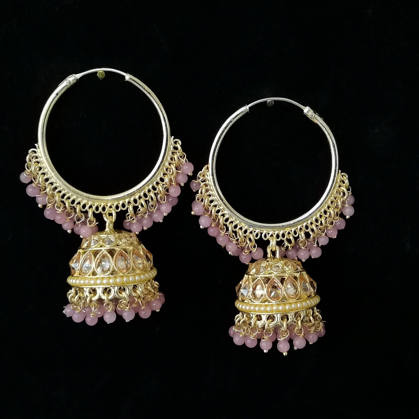 Pair of gold hoop earrings with pink gemstones on a black background