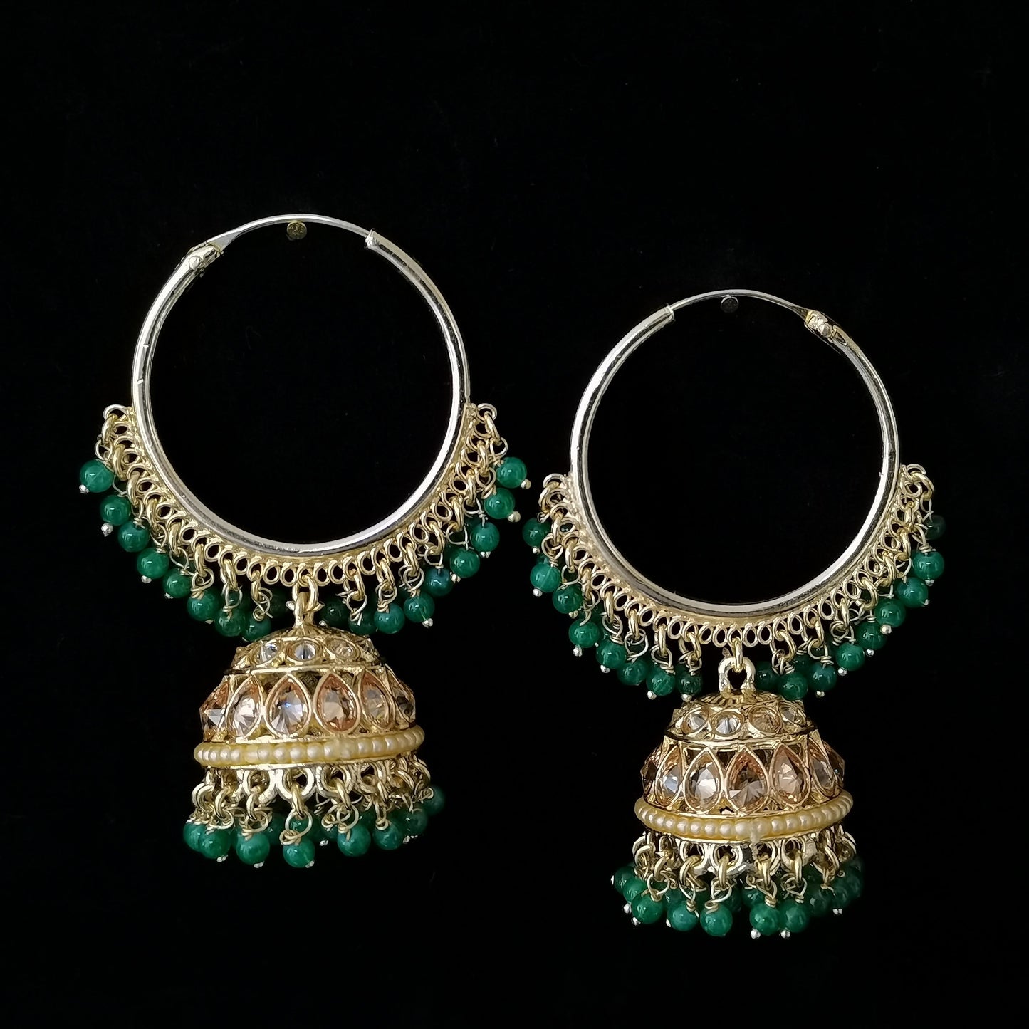 Ornate hoop earrings with green beads on a black background
