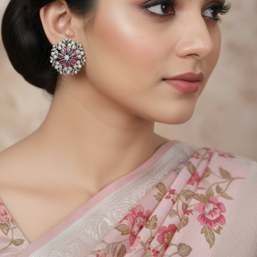 Pair of floral earrings with purple and clear stones on a gray background