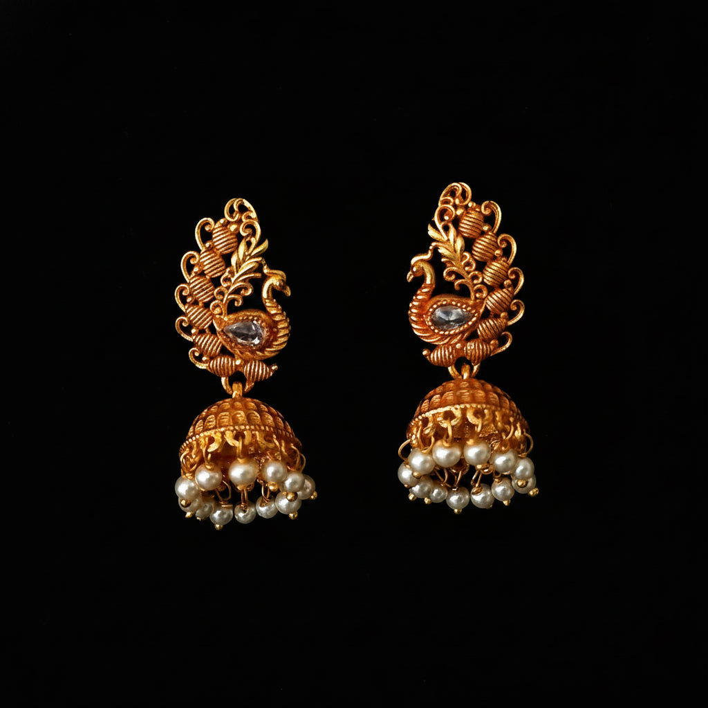 Gold earrings with pearl drops on a black background, branded 'Saheli'.