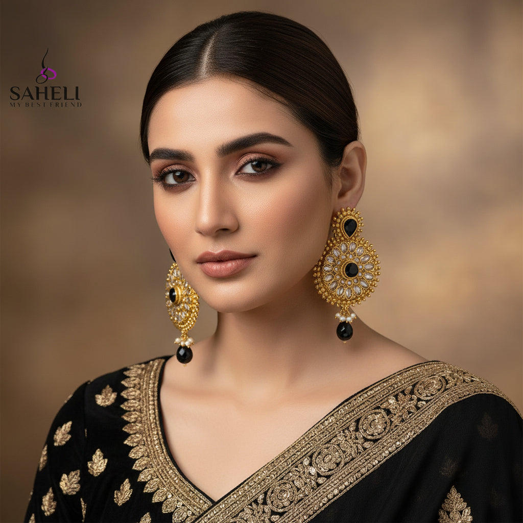 Gold and black earrings on a dark background with 'SAHELI' branding.