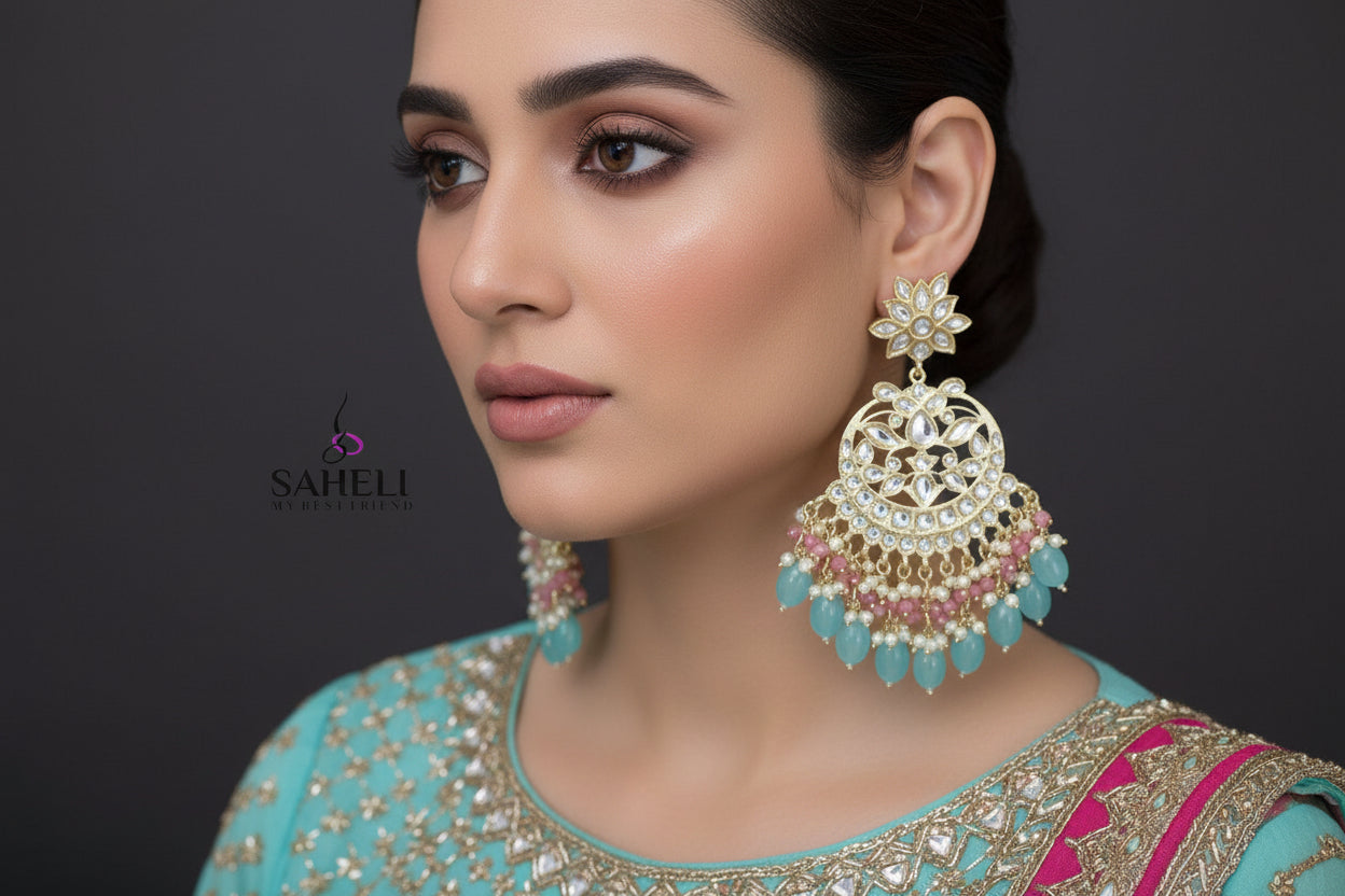 Ornate earrings with turquoise and pink stones on a dark background, featuring the brand 'Saheli'.