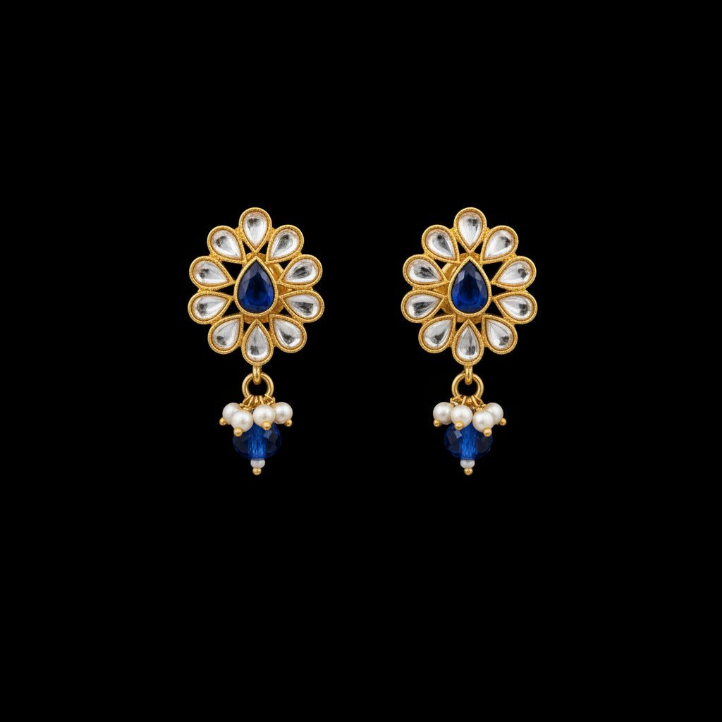 Gold and blue gemstone earrings on a gray stand with 'SAHELI' branding.