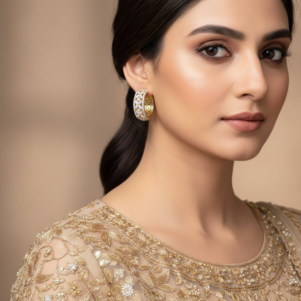 Gold hoop earrings with diamond accents on a gray background, featuring the brand 'Saheli'.