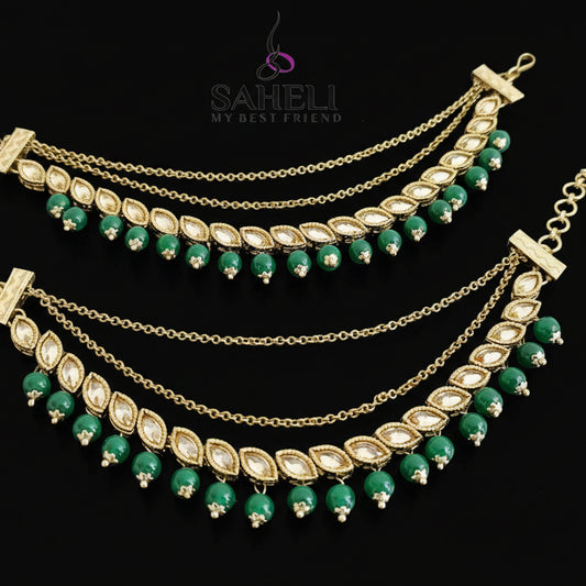Gold and green necklace with 'Saheli' branding on a dark background