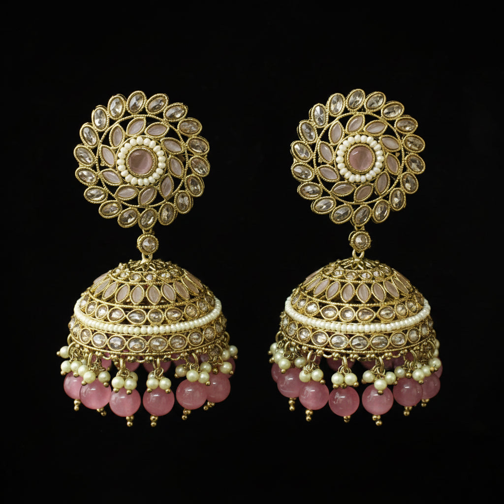 Pair of gold and pink earrings on a black stand against a black background