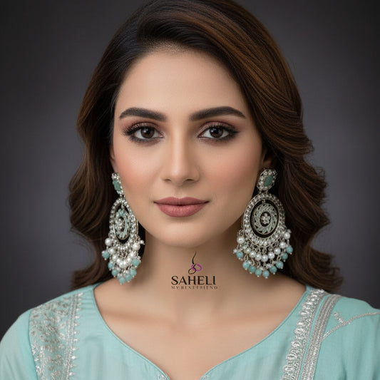 Pair of silver and turquoise earrings with 'SAHELI' branding on a dark background