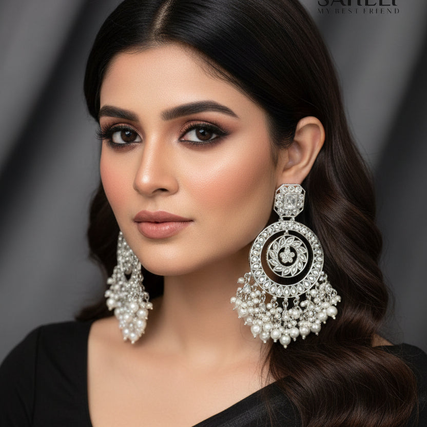 Pair of silver and pearl earrings with 'Saheeli' branding on a dark background