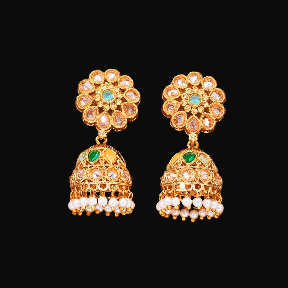 Pair of gold earrings with floral top and bell-shaped bottom on a brown background