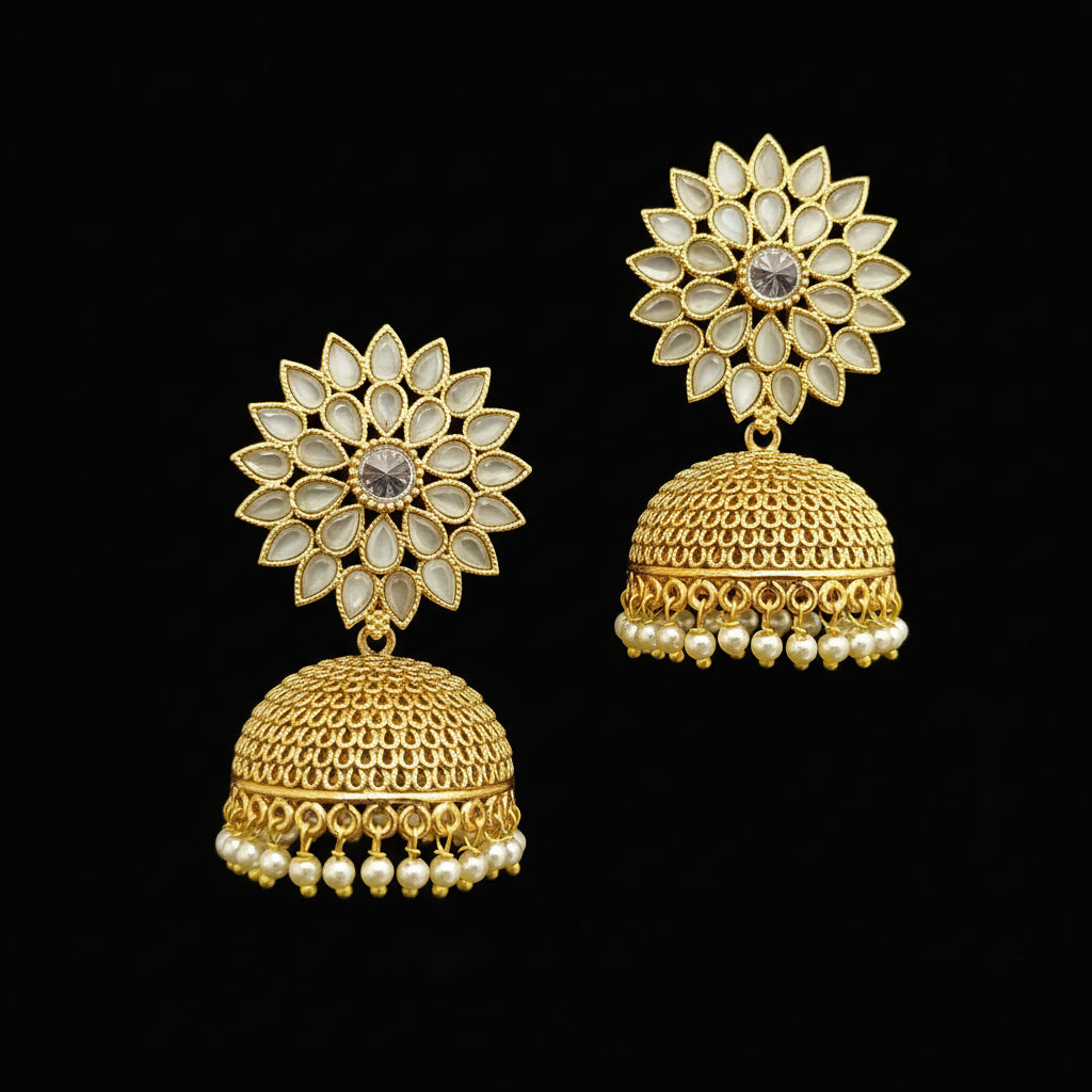Gold jhumka earrings with floral design on a gray stand against a light blue background