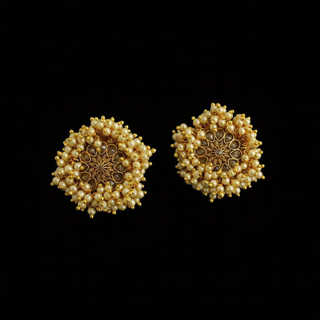 Pair of gold and pearl earrings on a dark background