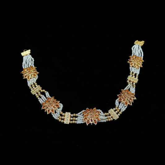 Decorative necklace with floral designs on a black background, featuring the brand 'Saheli'.