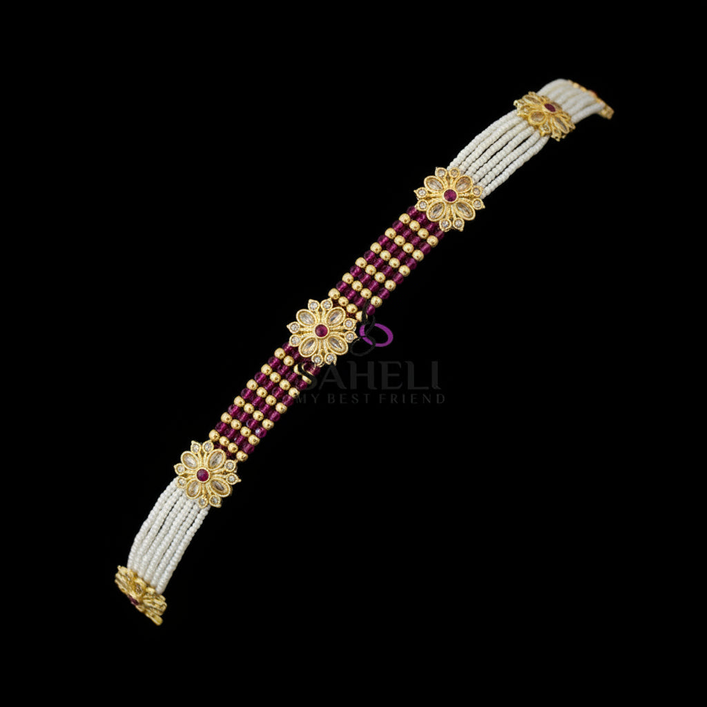 Bracelet with gold and red beads on a dark background, featuring the brand 'SAHELI'.
