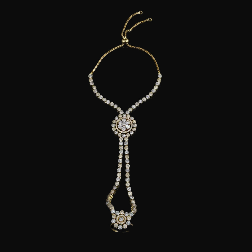 Gold-toned chain necklace with multiple rows of clear rhinestones, featuring a central oval cluster and a dangling floral pendant, displayed on a solid pink background.