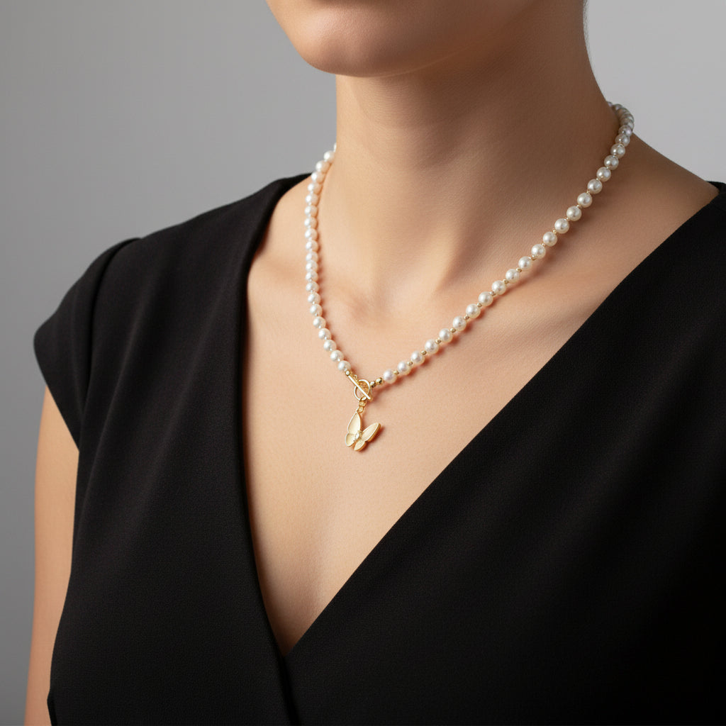 Pearl necklace with a gold butterfly pendant on a black background