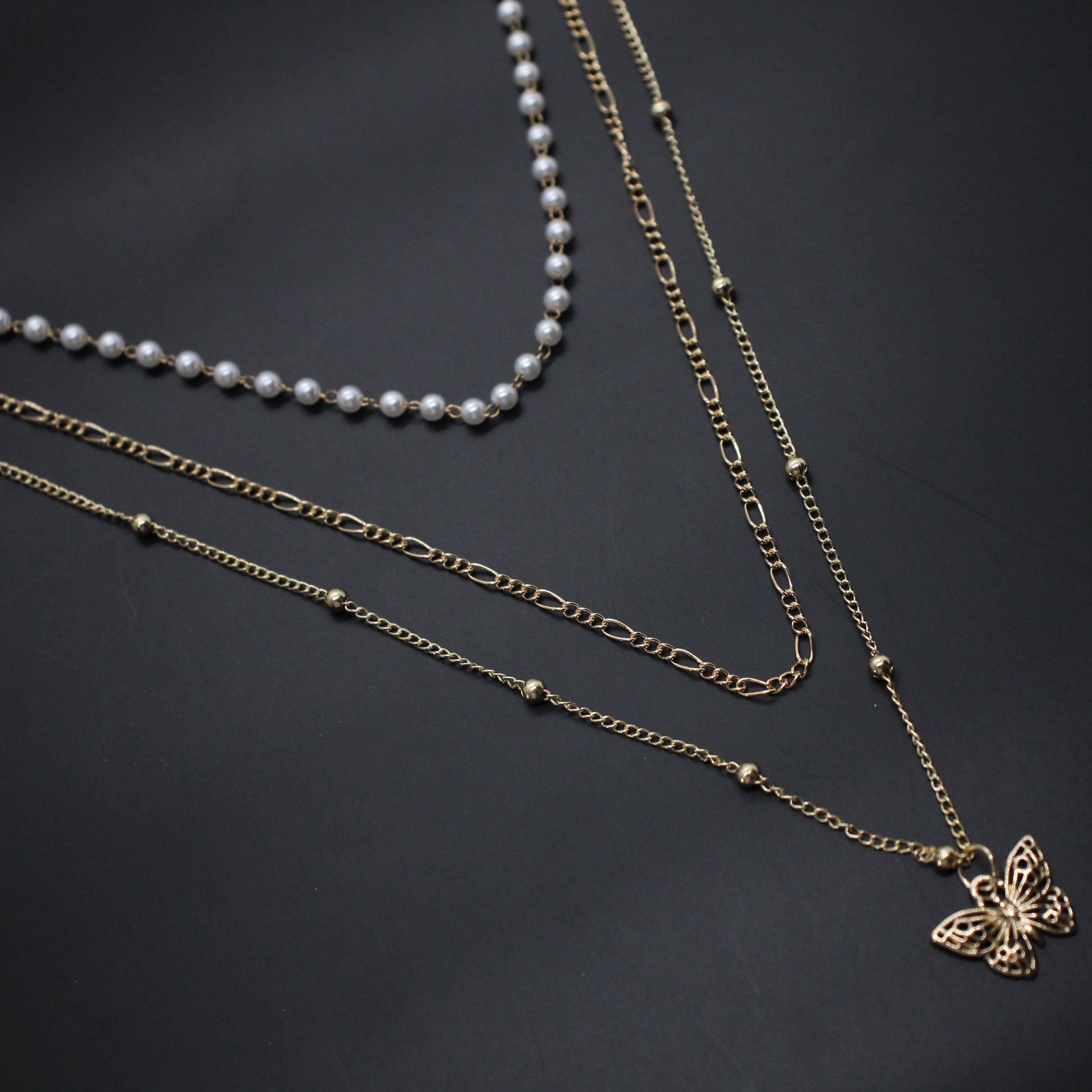 Three necklaces with different designs on a dark background