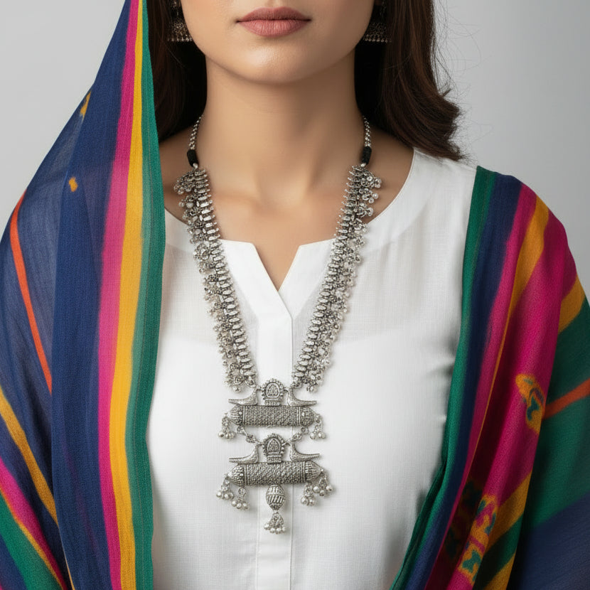 Silver necklace with intricate designs on a reflective surface
