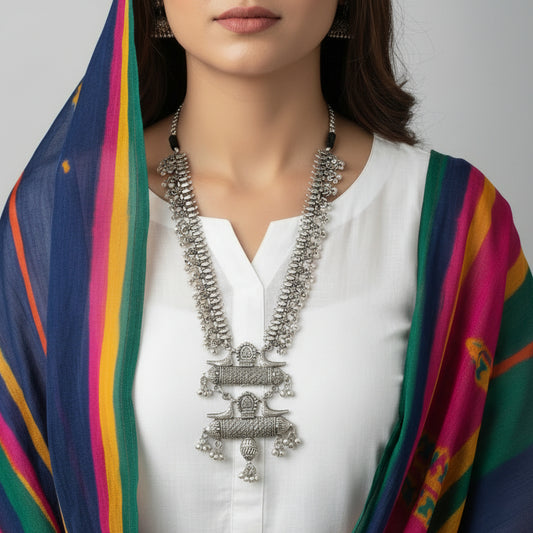 Silver necklace with intricate designs on a reflective surface
