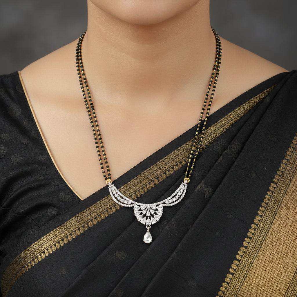 A traditional Indian Manglik necklace featuring a silver-toned paisley pendant adorned with clear stones, paired with a black beaded chain that has small gold accents.