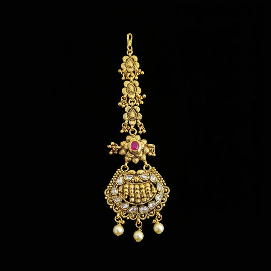 Gold necklace with a red gemstone on a dark background, branded 'SAHELI'.
