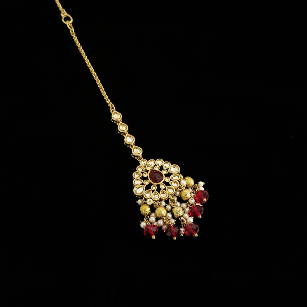 Gold and red gemstone pendant on a chain against a dark background