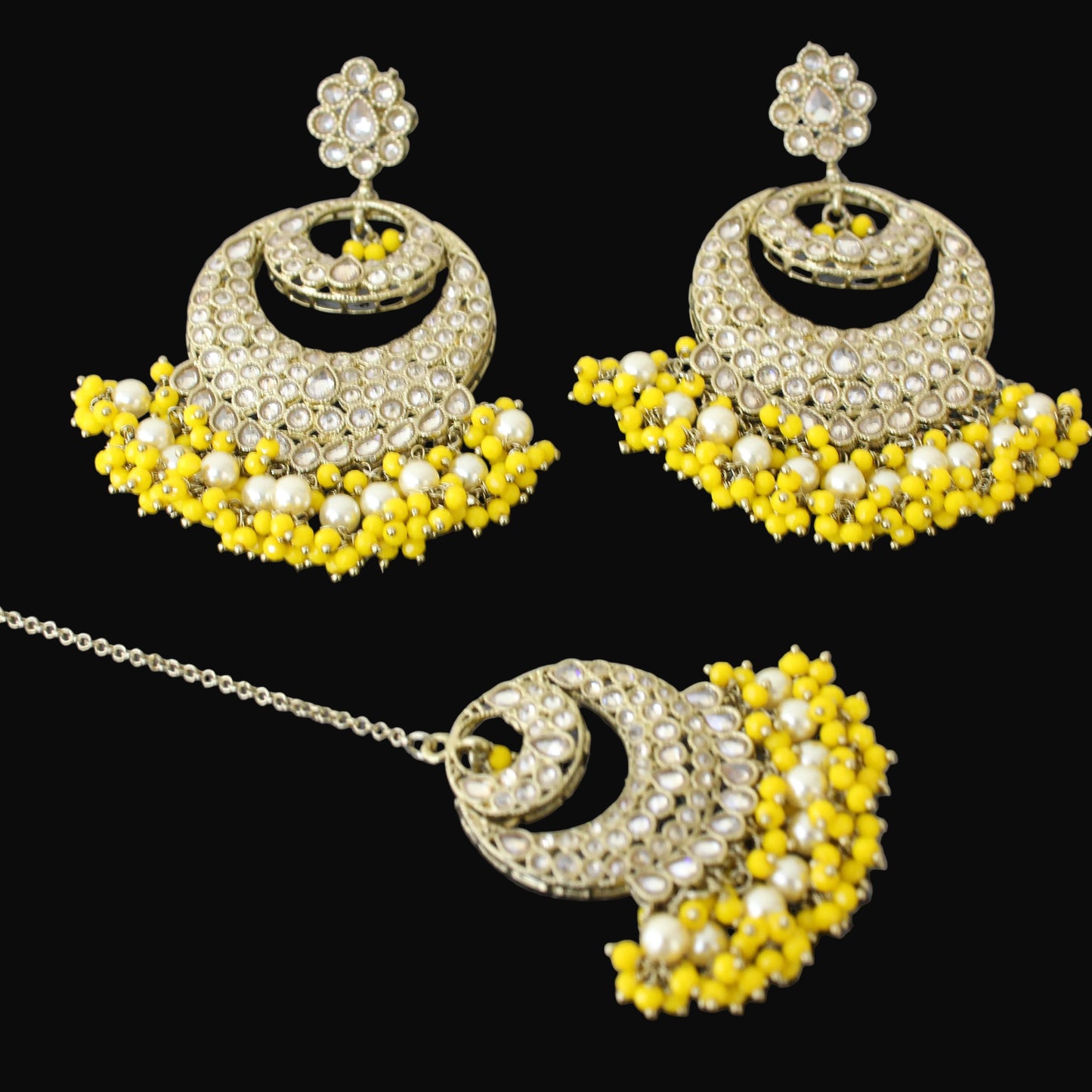 Ornate earrings with yellow and white stones on a dark background