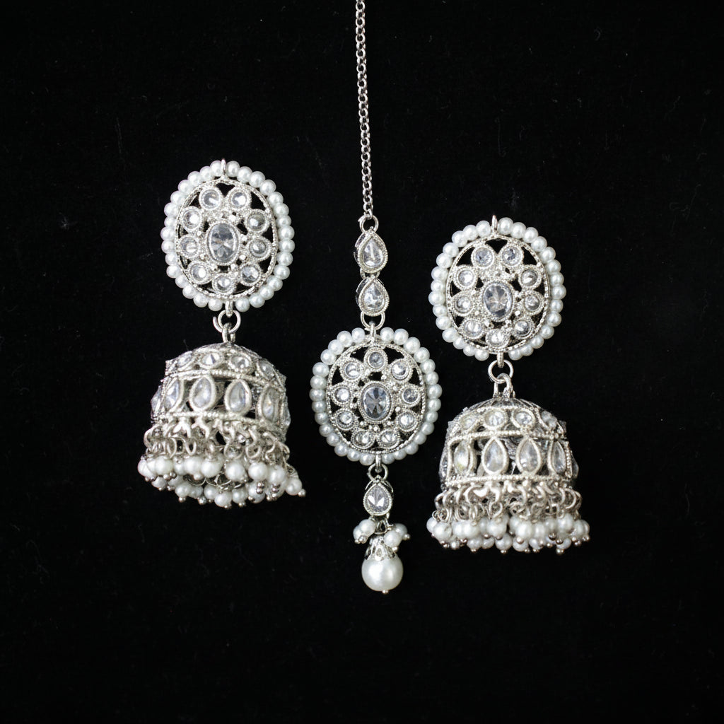 Silver jhumka earrings with pearl accents on a black background