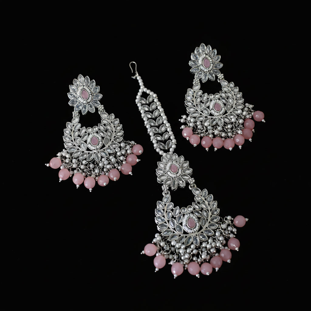 Jewelry set with silver and pink earrings on a dark background