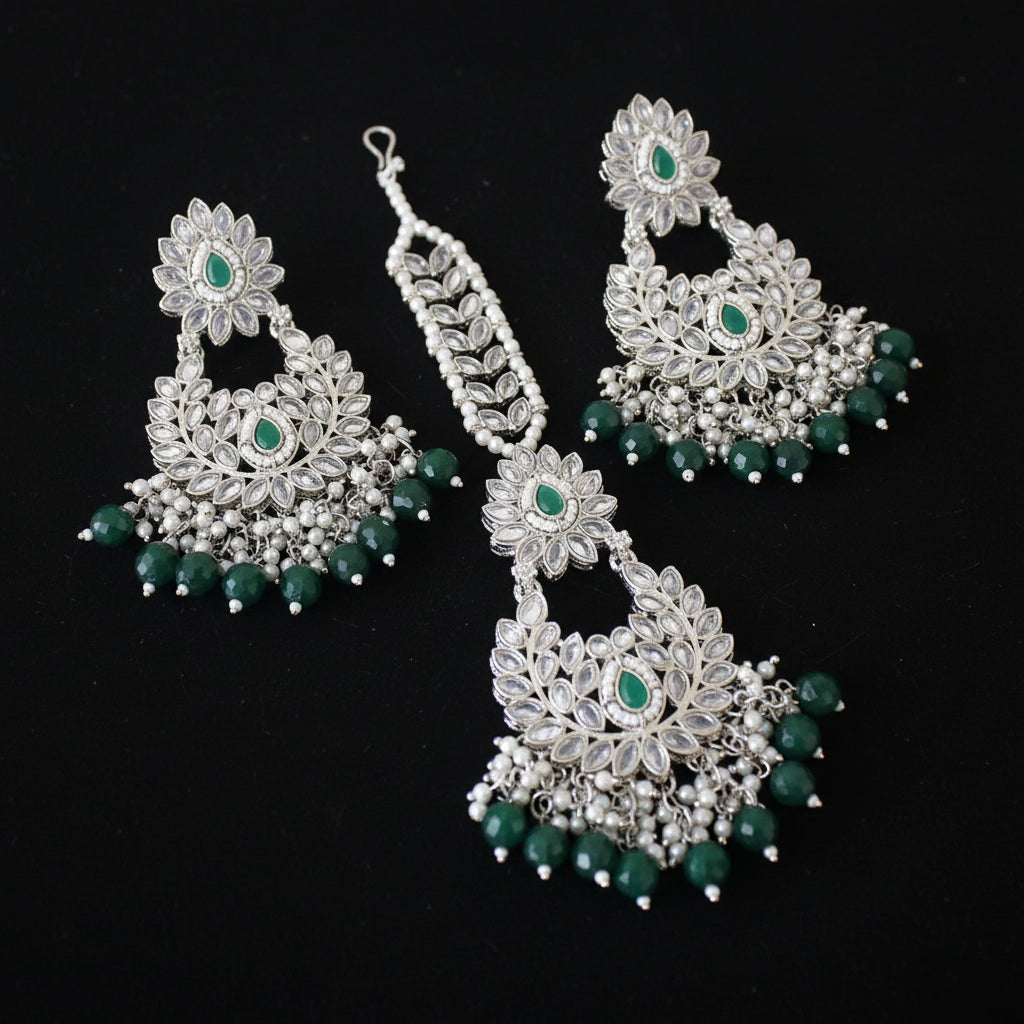 Set of silver and green earrings on a dark background