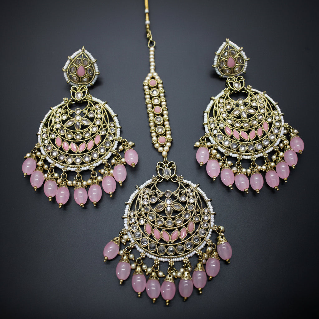 Ornate earrings with pink beads on a dark background