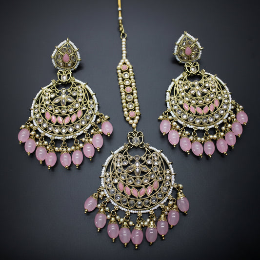 Ornate earrings with pink beads on a dark background