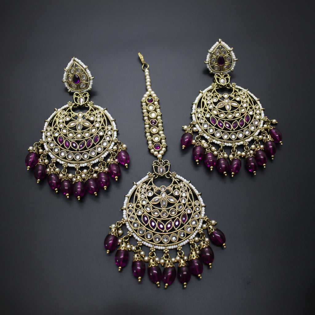 Ornate earrings with purple gemstones on a dark background