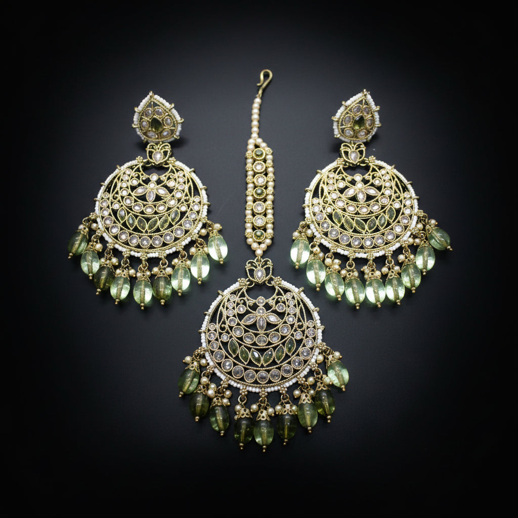 Ornate earrings with green beads on a dark background