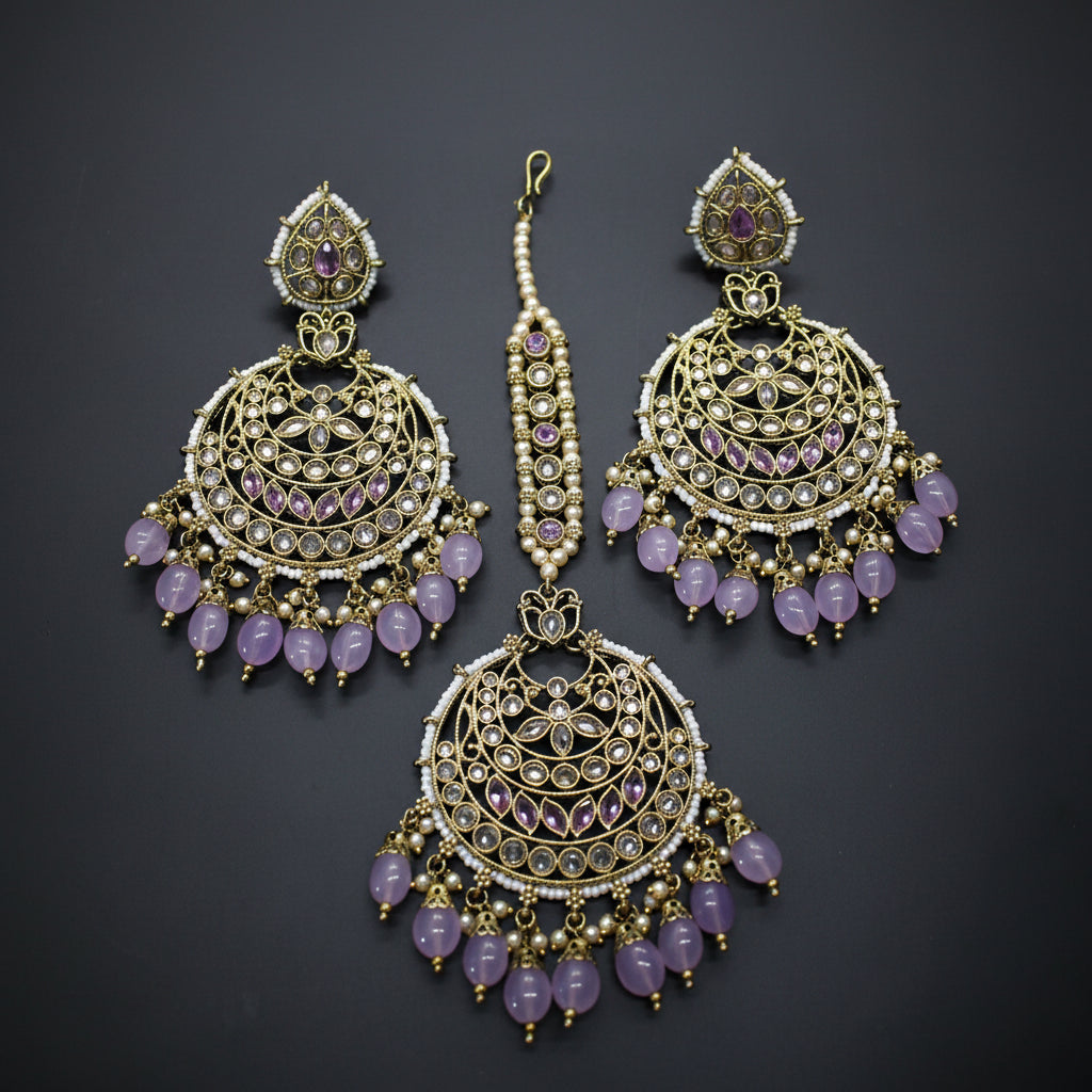 Ornate earrings with gold detailing and purple stones on a dark background