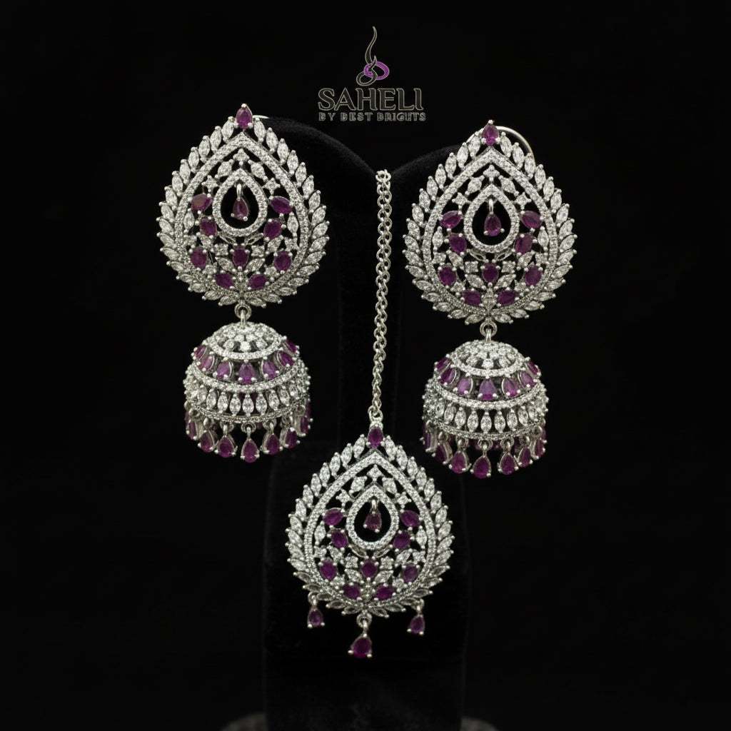 Silver earrings with red gemstones on a black stand, featuring the brand 'Saheli by Neha Heiden'.
