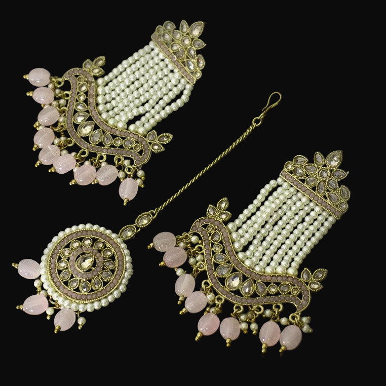 Set of decorative earrings and hairpin with pearl and stone details on a dark background