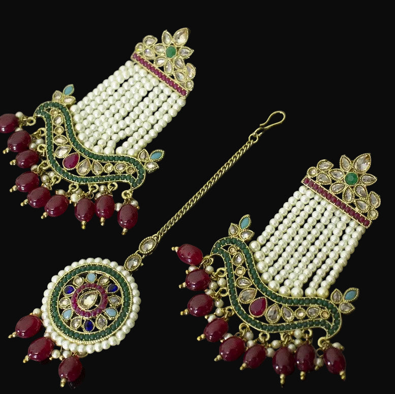 Ornate earrings with pearls, red stones, and gold accents on a dark background