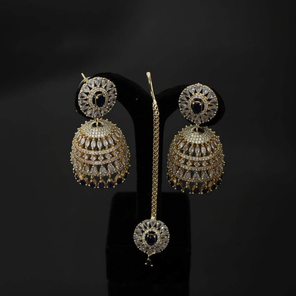 Gold and diamond earrings on a black stand with 'Saheli' branding.