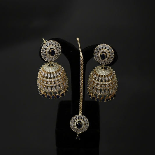 Gold and diamond earrings on a black stand with 'Saheli' branding.