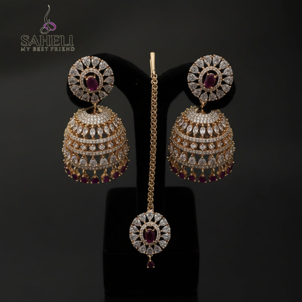 Gold and red gemstone earrings on a black stand with 'SAHeli' branding.