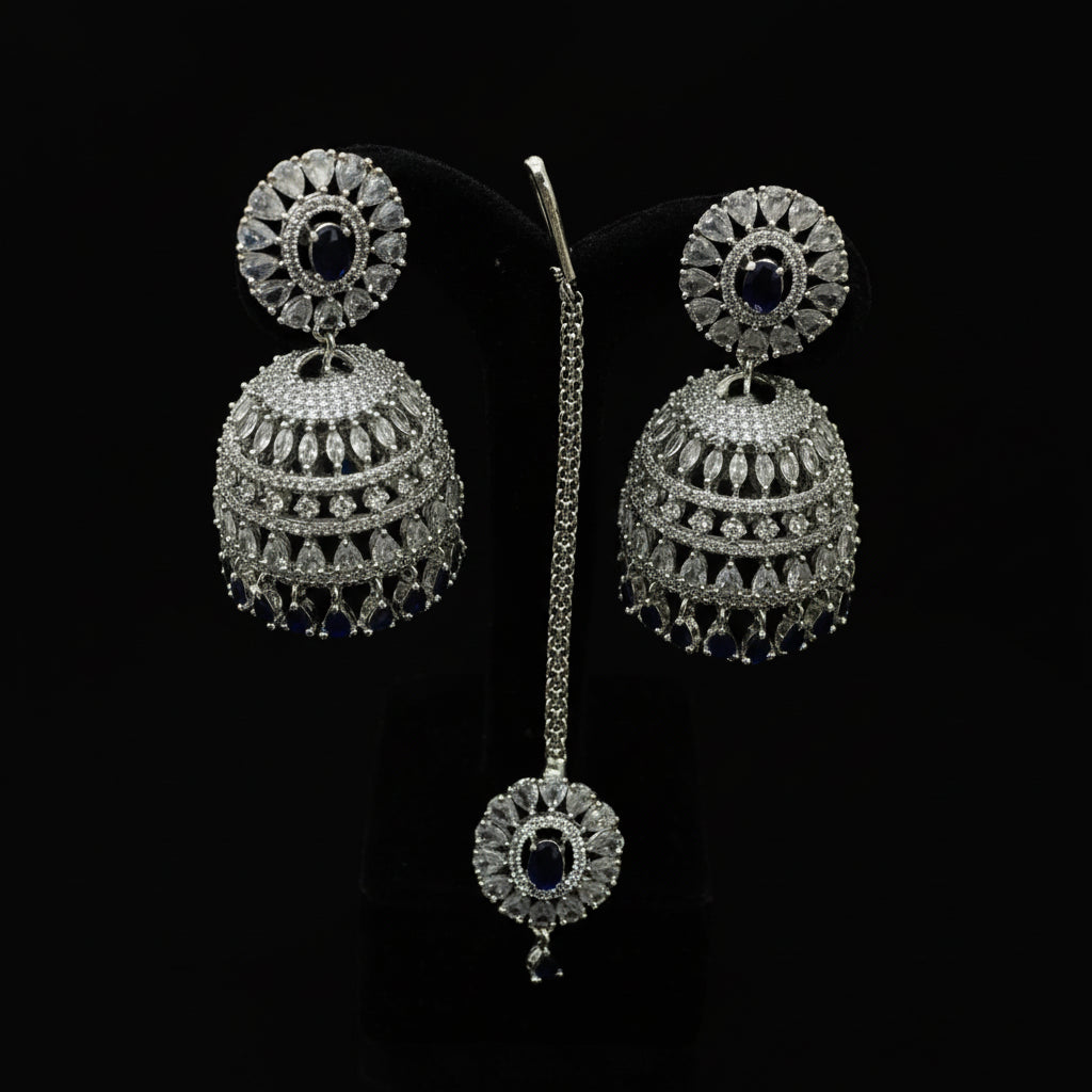 Silver earrings with blue stones on a black stand, branded 'Sanielli'.