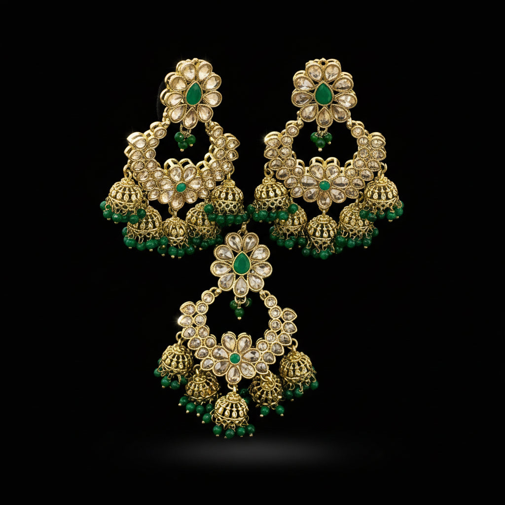 Gold and green earrings on a black stand with 'Saheli' branding.