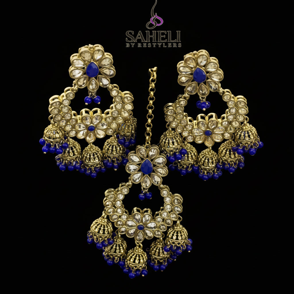 Gold and blue earrings on a black stand with 'Saheli' branding.