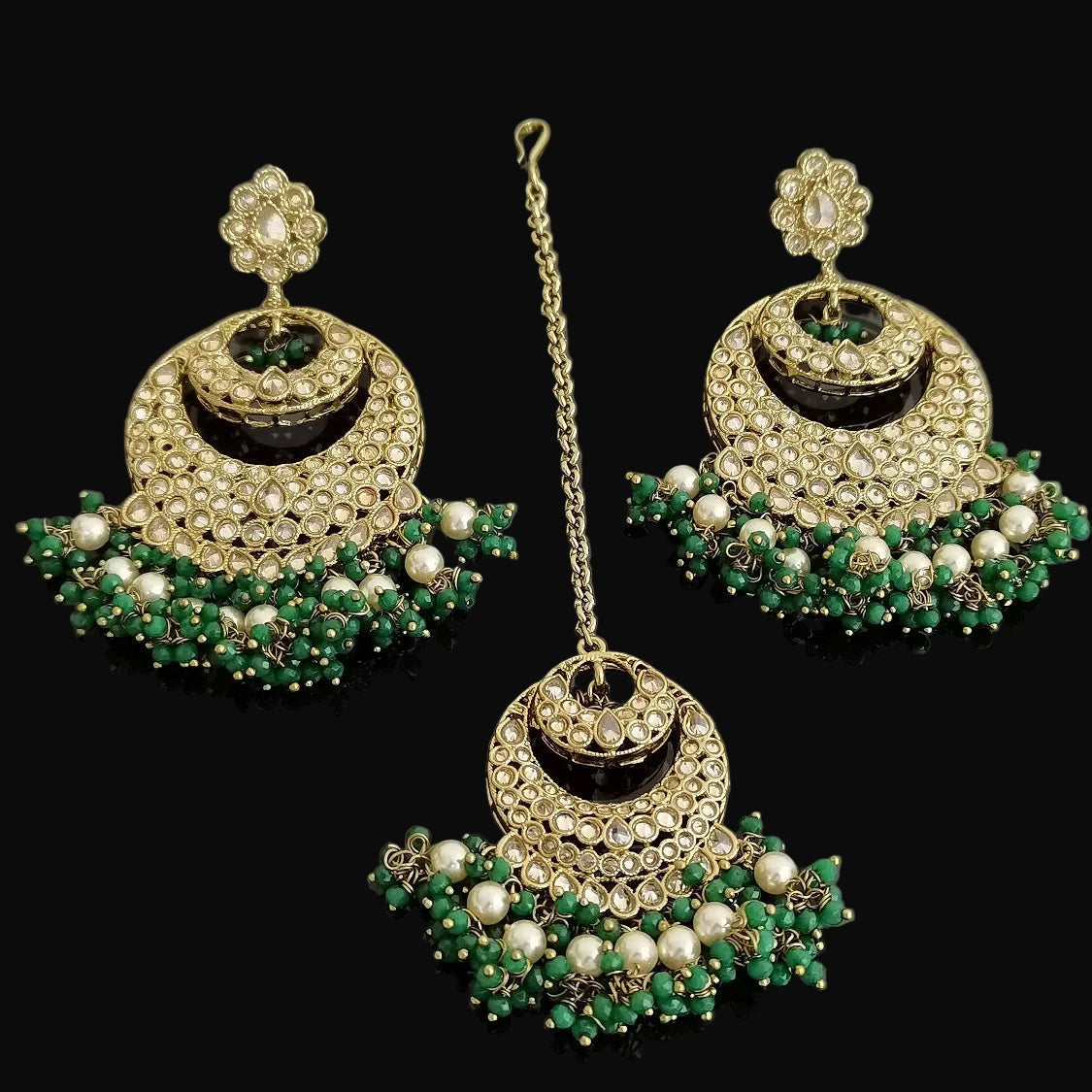 Set of gold, green, and pearl jewelry on a dark background
