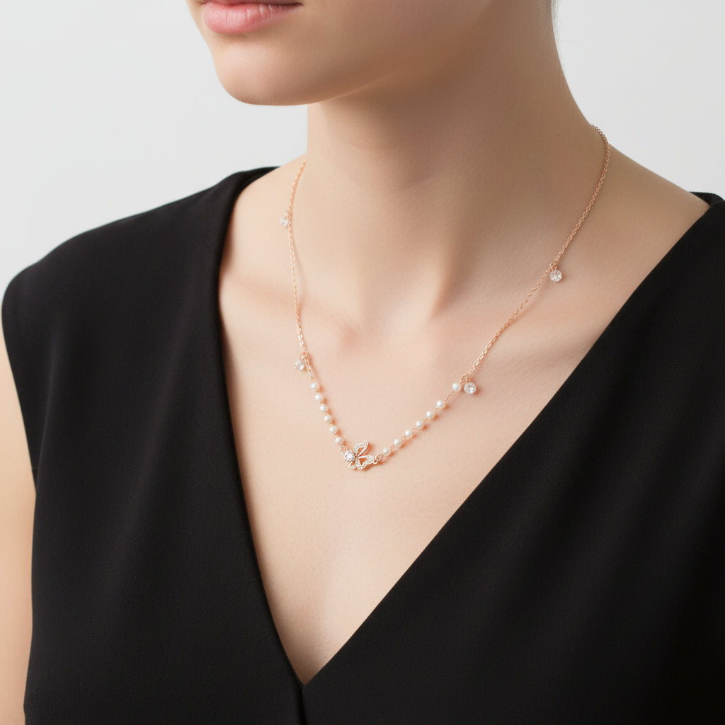 Delicate necklace with small beads and a butterfly pendant on a dark background