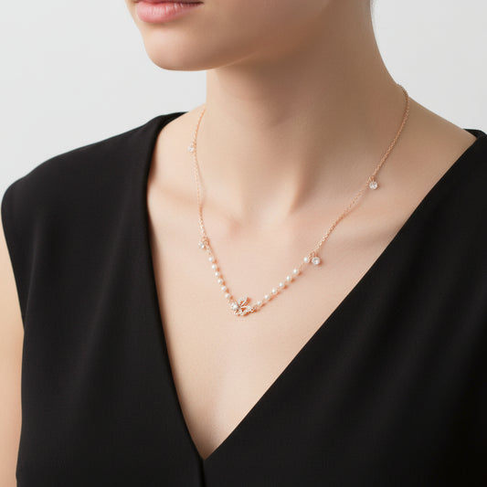 Delicate necklace with small beads and a butterfly pendant on a dark background