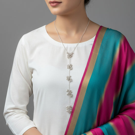 Silver necklace with floral designs on a gray background, branded 'Saheli'.